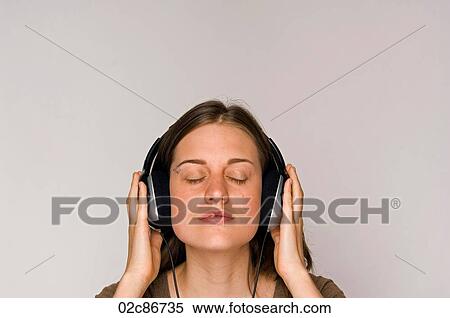 Stock Photography - Young woman intently listening to music on headphones.. Fotosearch