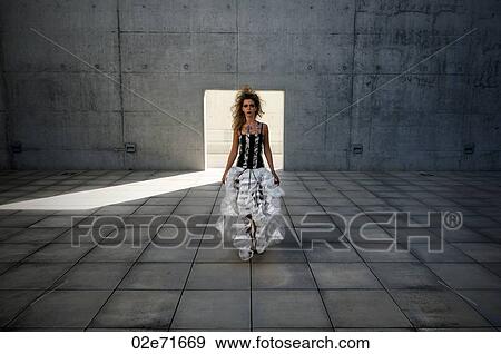 Stock Photo - A glamorous woman modern concrete courtyard. Fotosearch