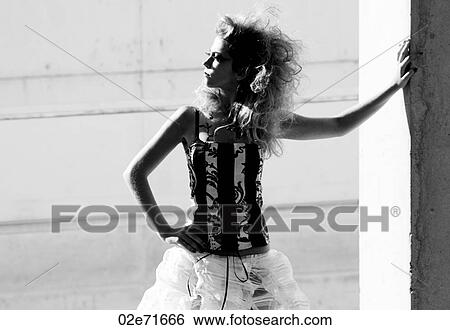 Stock Photograph - A glamorous women leaning against a concrete wall. Fotosearch