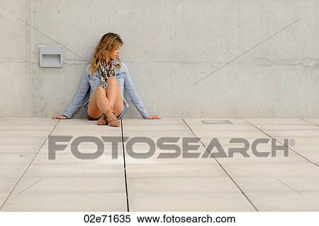 A stylish woman dressed in denim leaning against a wall View Large Photo Image Stock Photography - A stylish woman dressed in denim leaning against a wall. Fotosearch