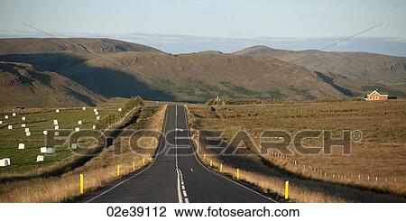 Asphalt highway through farmland and hay bales, leading to mountains View Large Photo Image Stock Image - Asphalt highway through farmland and hay bales, leading to mountains. Fotosearch