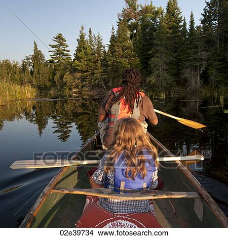 Picture - Back view of people rowing a canoe at Lake of the Woods, Ontario. Fotosearch