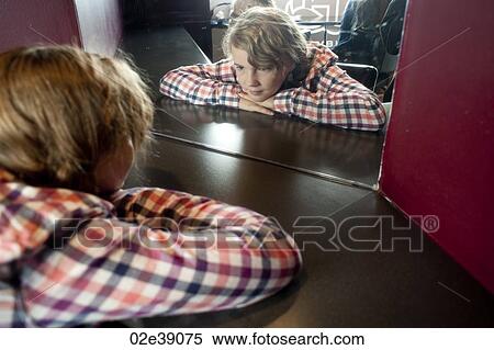 Blonde girl in check gingham shirt looking at reflection in mirror View Large Photo Image Stock Photography - Blonde girl in check gingham shirt looking at reflection in mirror. Fotosearch