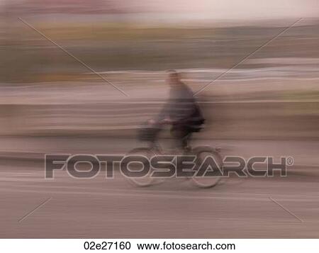 Stock Image - Blurred image of a person riding a bike in Paris France. Fotosearch