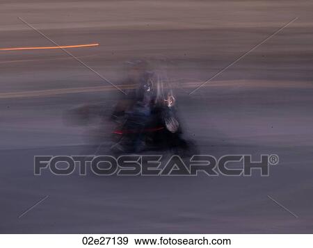 Stock Photo - Blurred image of a person riding a scooter in Paris France. Fotosearch