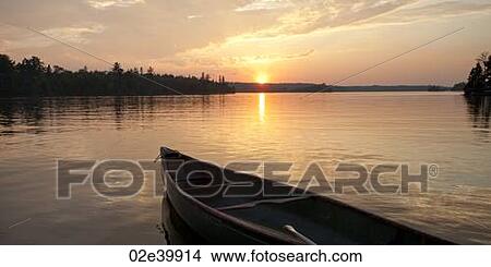 Picture - Bow of a canoe with the sunset in the horizon at Lake of the Woods, Ontario. Fotosearch