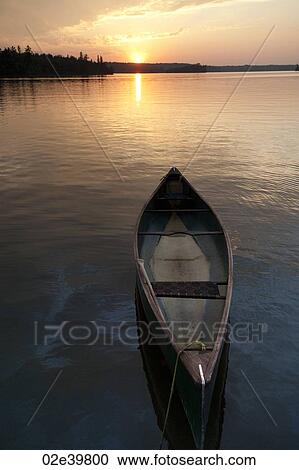 Stock Image - Canoe on the water with the sunset in horizon at Lake of the Woods, Ontario. Fotosearch