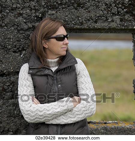 Casual portrait woman in sunglasses, down vest, and knit sweater, before rugged stone window frame View Large Photo Image Stock Photo - Casual portrait woman in sunglasses, down vest, and knit sweater, before rugged stone window frame . Fotosearch