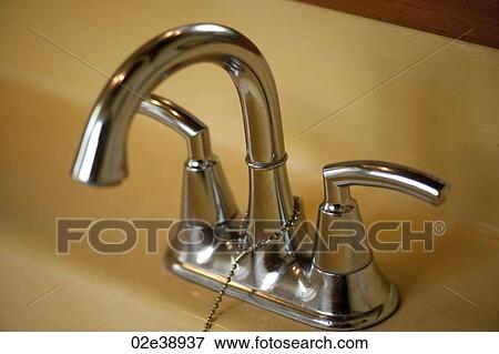 Chrome bathroom double handle faucet and taps with a plug chain on a yellow basin View Large Photo Image Stock Photo - Chrome bathroom double handle faucet and taps with a plug chain on a yellow basin. Fotosearch