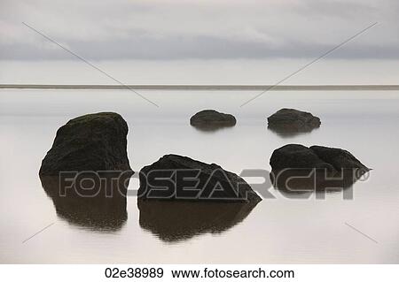 Circle of five black rocks rising from the ocean, mirrored in the water, horizon in the background View Large Photo Image Stock Photo - Circle of five black rocks rising from the ocean, mirrored in the water, horizon in the background. Fotosearch