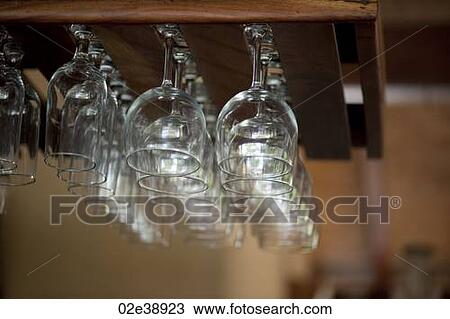Stock Image - Clean reflective glassware hanging from a wineglass rack. Fotosearch