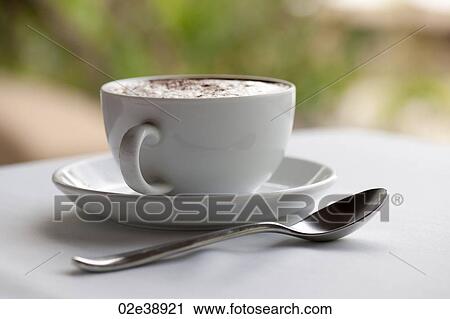 Cofffee cup, saucer and teaspoon, filled with steamed milk and sprinkled with spice, on a white table View Large Photo Image Stock Image - Cofffee cup, saucer and teaspoon, filled with steamed milk and sprinkled with spice, on a white table. Fotosearch