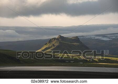 Craggy mountain rising above verdant grassland View Large Photo Image Stock Image - Craggy mountain rising above verdant grassland. Fotosearch