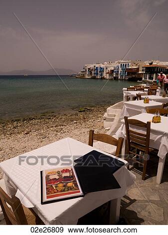Empty table and chairs by seashore in Mykonos Greece View Large Photo Image Stock Photo - Empty table and chairs by seashore in Mykonos Greece. Fotosearch