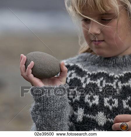 Stock Image - Girl holding egg shaped stone. Fotosearch