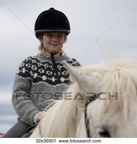Stock Image - Girl in riding helmet riding Icelandic horse. Fotosearch