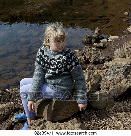 Girl in sweater sitting on rocks by lakeshore View Large Photo Image Stock Image - Girl in sweater sitting on rocks by lakeshore. Fotosearch