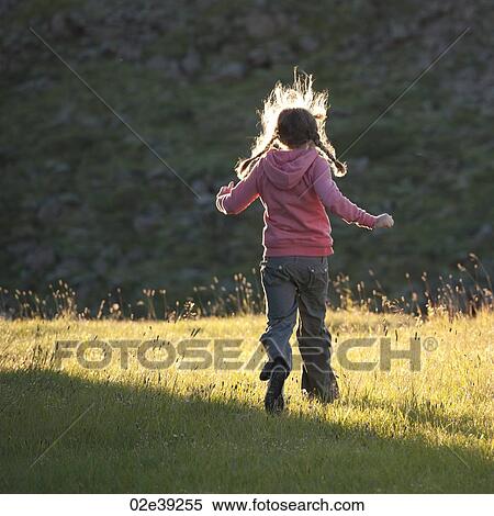 Stock Photography - Girl running through a sunlit meadow. Fotosearch