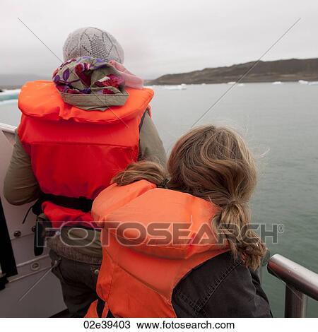 Girls in fluorescent orange life preservers on boat on glacial lake View Large Photo Image Stock Image - Girls in fluorescent orange life preservers on boat on glacial lake. Fotosearch