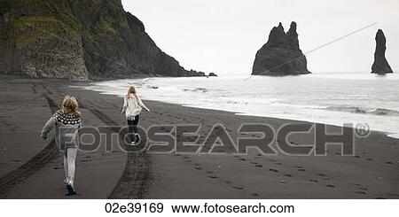 Girls running on black volcanic sand beach with tire tracks and footprints, cliffs View Large Photo Image Stock Photo - Girls running on black volcanic sand beach with tire tracks and footprints, cliffs . Fotosearch
