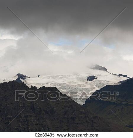 Glacier icecap on jagged mountain, surrounded by clouds View Large Photo Image Stock Photography - Glacier icecap on jagged mountain, surrounded by clouds. Fotosearch