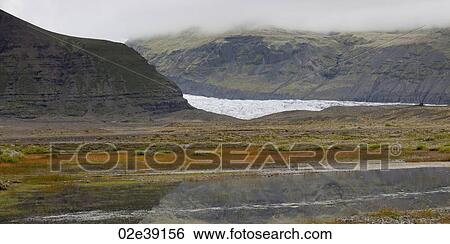 Glacier in misty rugged mountain valley, with water body reflecting the sky View Large Photo Image Stock Photograph - Glacier in misty rugged mountain valley, with water body reflecting the sky. Fotosearch