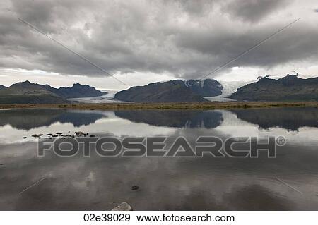 Grey mountains glaciers and dark clouds reflected in the lake View Large Photo Image Stock Photo - Grey mountains glaciers and dark clouds reflected in the lake. Fotosearch
