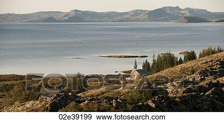 Houses on rugged hillside, with body of calm water, and mountains in distance View Large Photo Image Stock Photo - Houses on rugged hillside, with body of calm water, and mountains in distance. Fotosearch