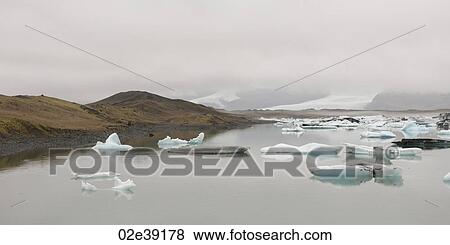 Icebergs floating in the ocean along a misty coastline View Large Photo Image Stock Photo - Icebergs floating in the ocean along a misty coastline. Fotosearch