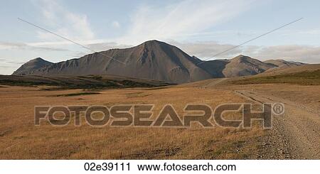 Stock Image - Landscape, dry grass pasture with road before eroded volcanic mountain. Fotosearch