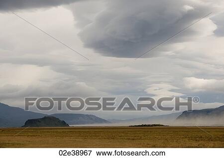 Landscape of barren meadow before mountains, with grey cloudy skies View Large Photo Image Stock Photo - Landscape of barren meadow before mountains, with grey cloudy skies. Fotosearch