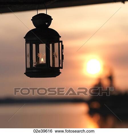 Stock Photograph - Lantern with the sunset horizon at Lake of the Woods, Ontario. Fotosearch