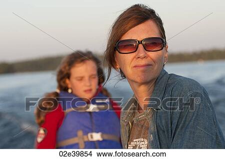 Mother and daughter with the sunlight in their face while riding in a boat at Lake of the Woods, Ontario View Large Photo Image Picture - Mother and daughter with the sunlight in their face while riding in a boat at Lake of the Woods, Ontario. Fotosearch
