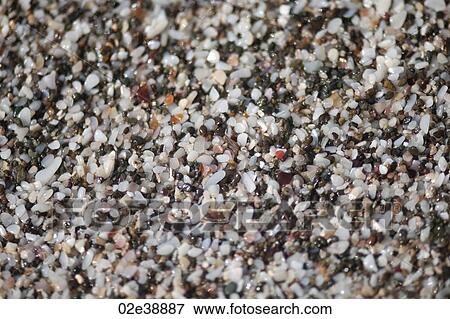 Stock Photo - Multicoloured wet quartz pebbles rounded by wave action on the beach. Fotosearch