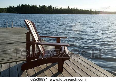 Picture - Muskoka chair on the dock overlooking the lake at Lake of the Woods, Ontario. Fotosearch