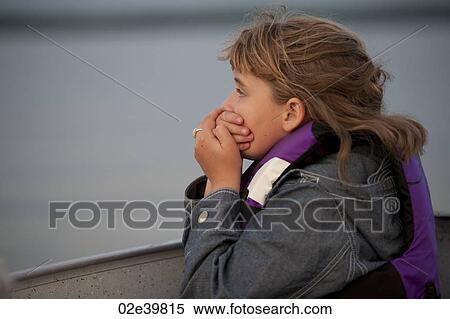 Stock Photography - Profile of a young girl holding her hands over her mouth . Fotosearch