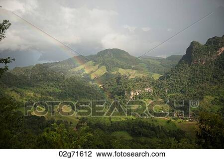 Stock Image - Rainbow over a mountain range, Thailand. Fotosearch