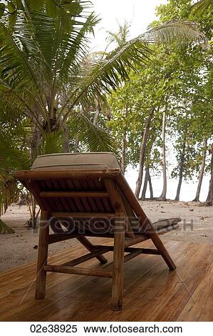Reclining wood lounge chair on a wooden deck facing jungle trees View Large Photo Image Stock Photography - Reclining wood lounge chair on a wooden deck facing jungle trees. Fotosearch