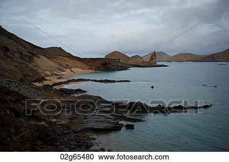 Stock Image - Rocky coast with Pinnacle Rock in the background, Bartolome island, Galapagos Islands, Ecuador. Fotosearch
