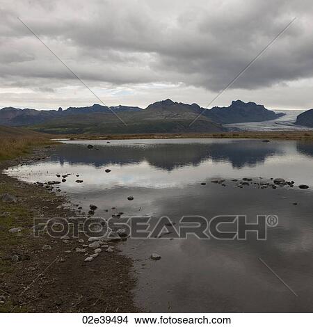 Rocky shoreline of glacial lake, mountains and glacier in distance View Large Photo Image Picture - Rocky shoreline of glacial lake, mountains and glacier in distance. Fotosearch