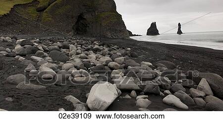 Rocky shoreline with cave, black volcanic sand, stacks offshore View Large Photo Image Stock Photo - Rocky shoreline with cave, black volcanic sand, stacks offshore. Fotosearch