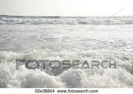 Picture - rolling ocean waves parallel to the horizon on an overcast day. Fotosearch