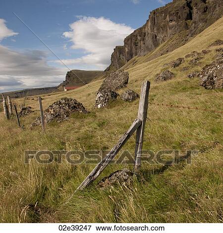 Stock Photo - Rural farmland pasture on mountainside with wire fence post. Fotosearch
