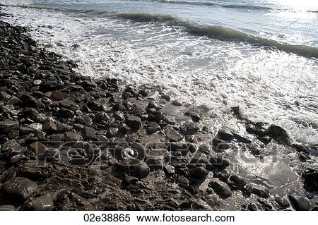 Shimmering waves on a rocky beach View Large Photo Image Stock Photography - Shimmering waves on a rocky beach. Fotosearch