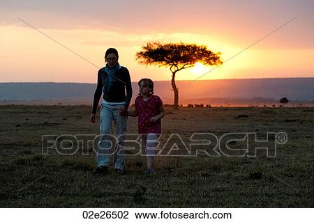 Stock Image - Sillouette of people against sunset sky in Kenya. Fotosearch