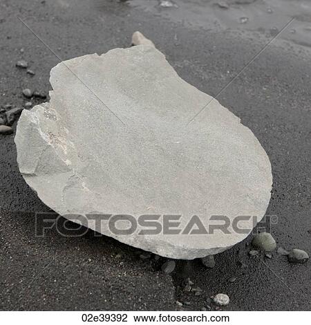 Stock Image - Split rock on wet volanic sand. Fotosearch