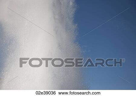 Stock Photograph - Spray of geyser steam in the blue sky. Fotosearch