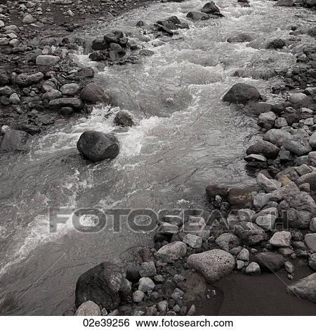 Stream flowing through rocky riverbed View Large Photo Image Stock Photograph - Stream flowing through rocky riverbed. Fotosearch