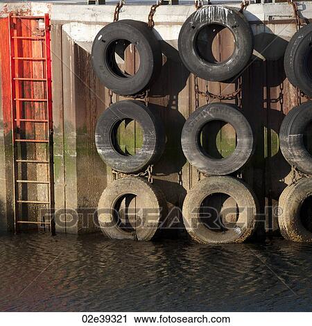 Tide marked tires hanging on a wharf next to a ladder down to the water View Large Photo Image Stock Image - Tide marked tires hanging on a wharf next to a ladder down to the water. Fotosearch