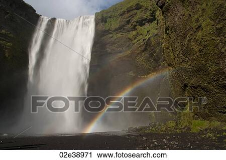 Waterfall cascading over a green rock cliff, with a double rainbow coming from the mist from the lake View Large Photo Image Stock Image - Waterfall cascading over a green rock cliff, with a double rainbow coming from the mist from the lake. Fotosearch
